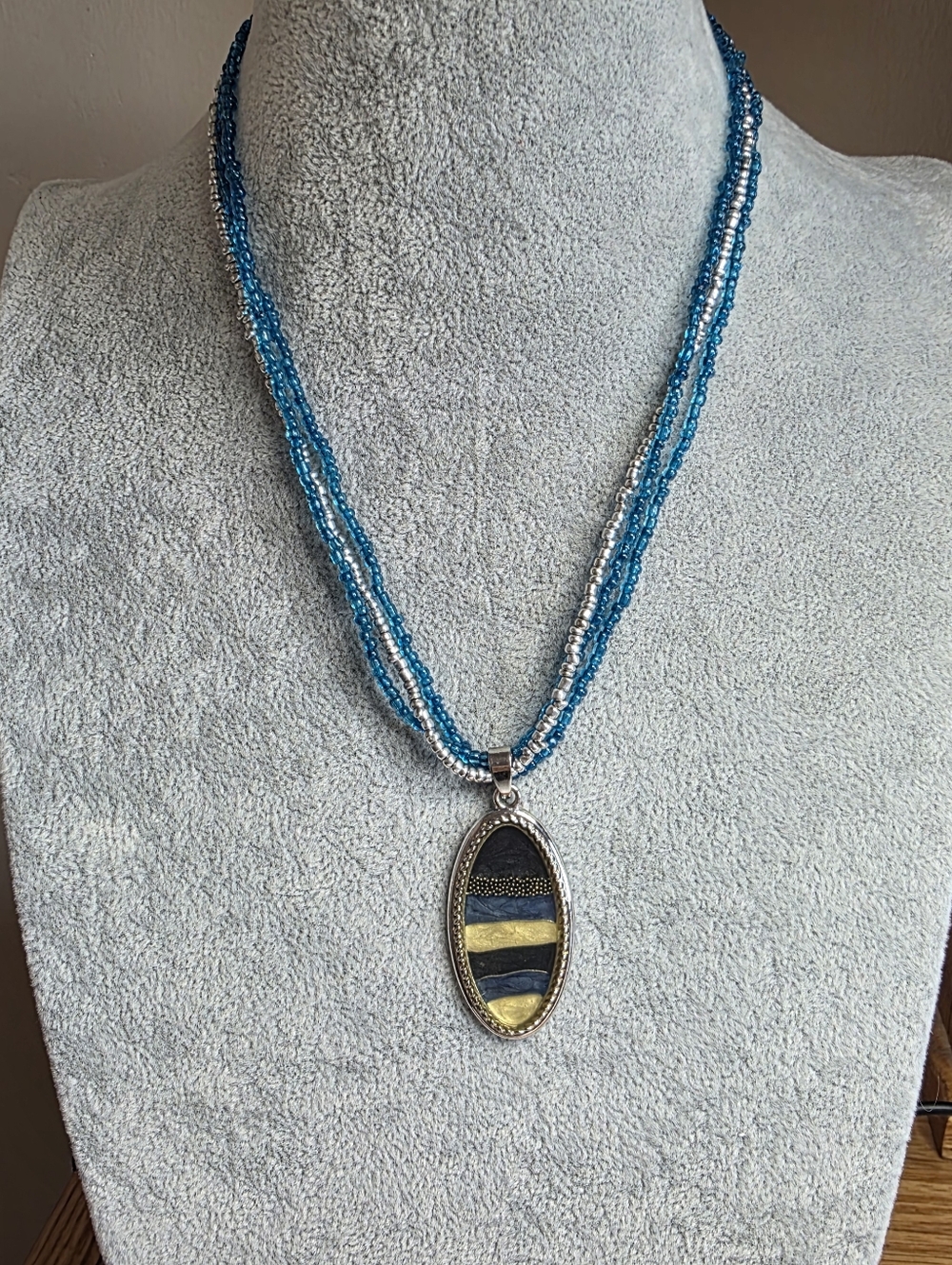 Blue and Silver Glass Beaded Necklace with a Silver, Gold & Black Oval Pendant